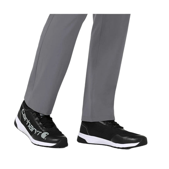 Black athletic work shoes with white midsoles worn with gray scrub pants