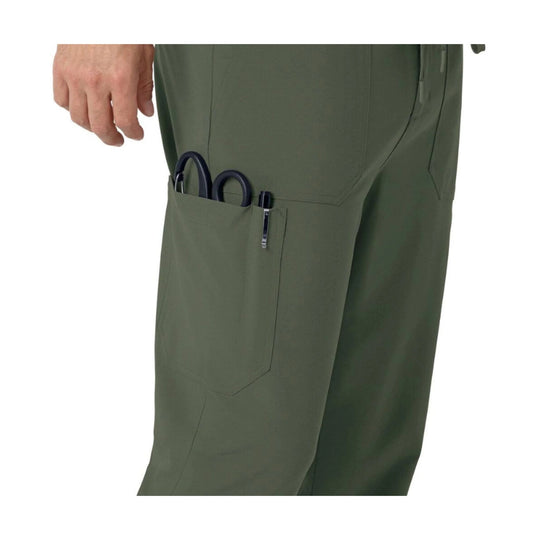 Olive scrub pants with side cargo pocket holding scissors and a pen