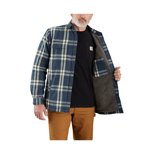 Blue plaid sherpa-lined shirt jacket open over a black T-shirt, shown on a model with chest pocket and front buttons.