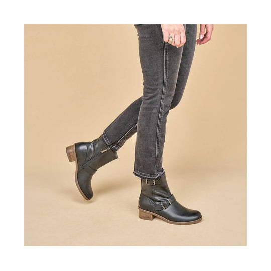 Black ankle boots with buckle straps, stacked heels, and side zippers worn with dark jeans.