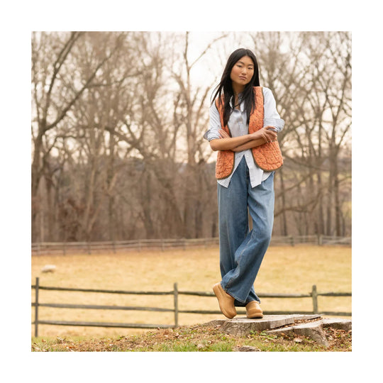 Tan slip-on clogs with a rounded toe worn with wide-leg jeans outdoors