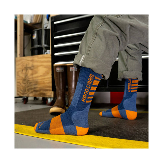 Blue and orange work socks with "Darn Tough" text on the leg, worn with rolled gray pants
