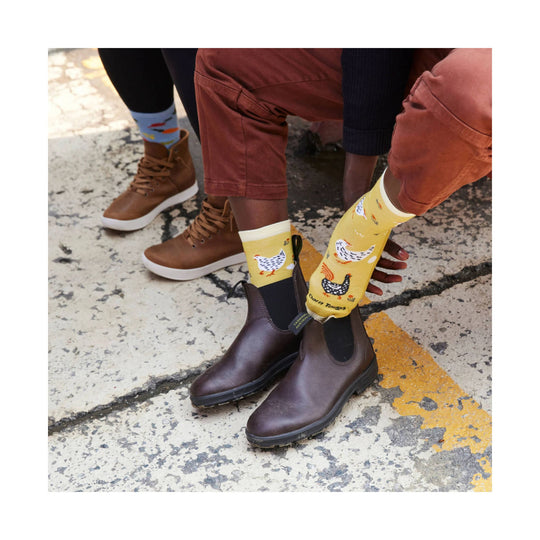 Yellow crew socks with chicken and rooster graphics worn with brown Chelsea boots