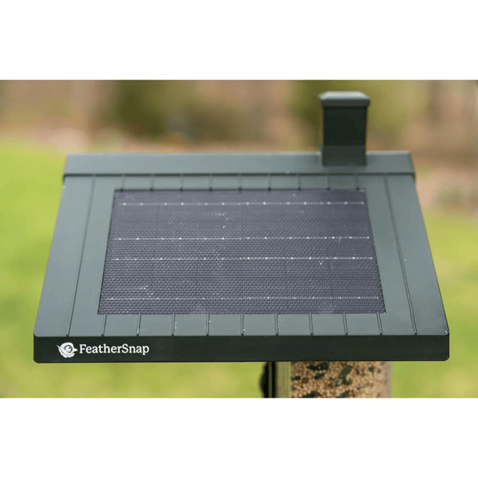 Black solar bird feeder with mounted rooftop panel and small chimney on top
