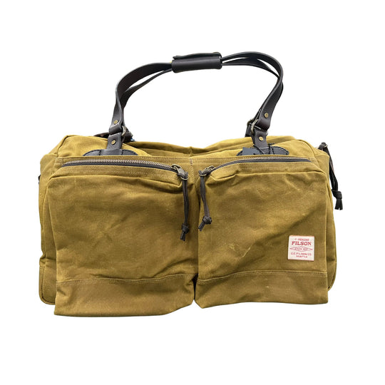 Olive canvas duffel bag with black leather handles, front zipper pockets, and a logo patch
