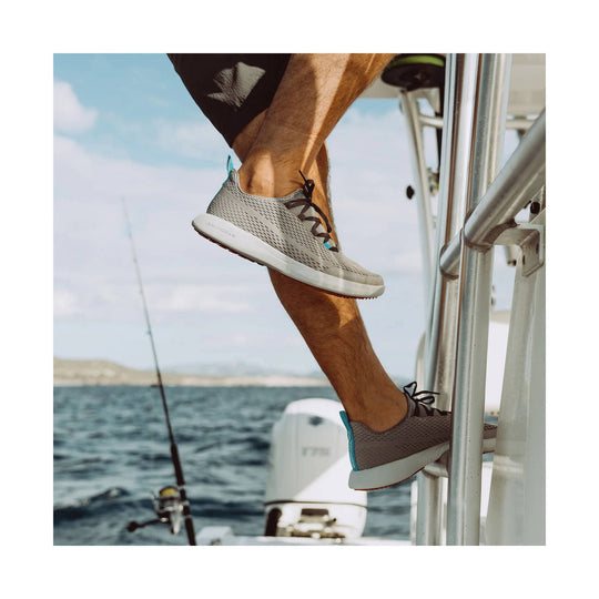 Gray knit boat shoes with bungee laces and white soles, shown on feet climbing a boat ladder