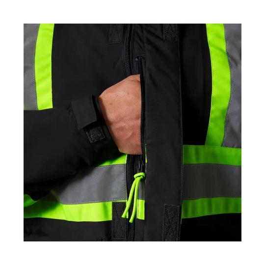 Black high-visibility jacket with neon yellow reflective stripes, shown close up with hand in the zippered chest pocket
