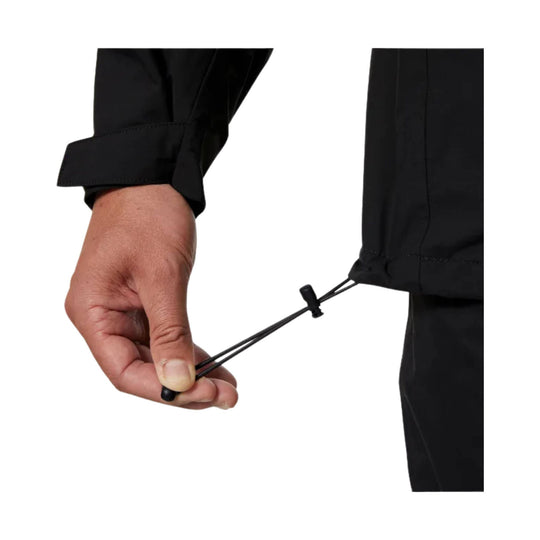 Black jacket cuff with adjustable elastic hem cord being tightened by hand