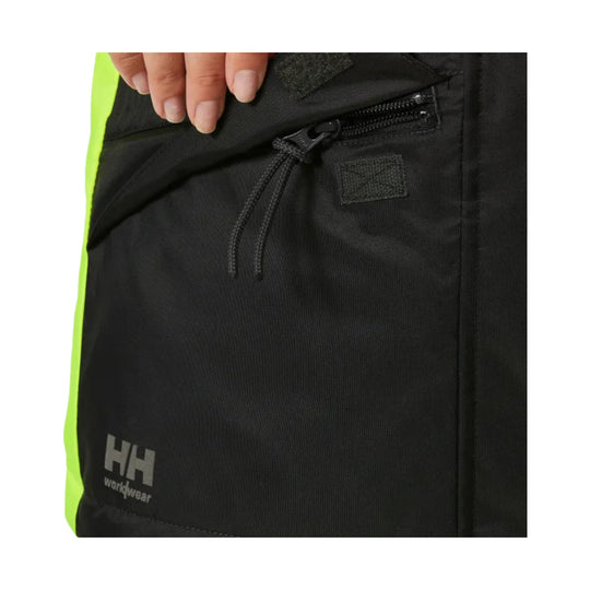 Black workwear jacket pocket with neon yellow side panel, zipper, and HH Workwear logo