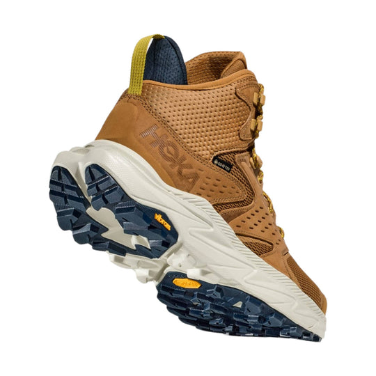 Tan mid-top hiking boot with dark blue outsole and gold heel pull tab