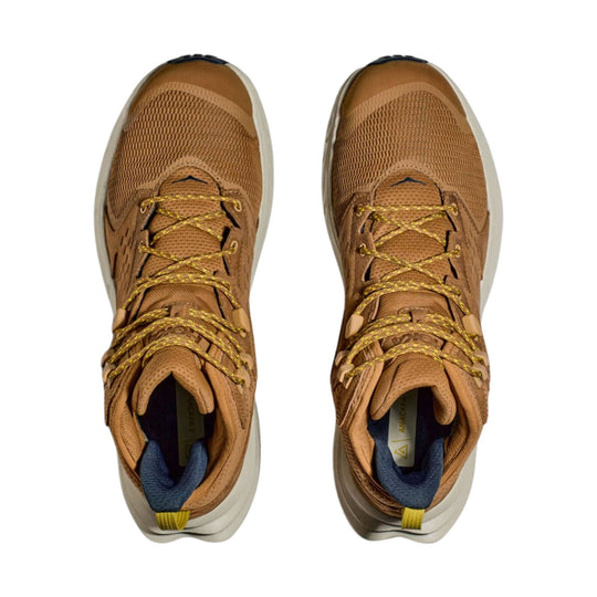Pair of tan mid-top hiking shoes with yellow laces, blue collars, and white soles, shown from above