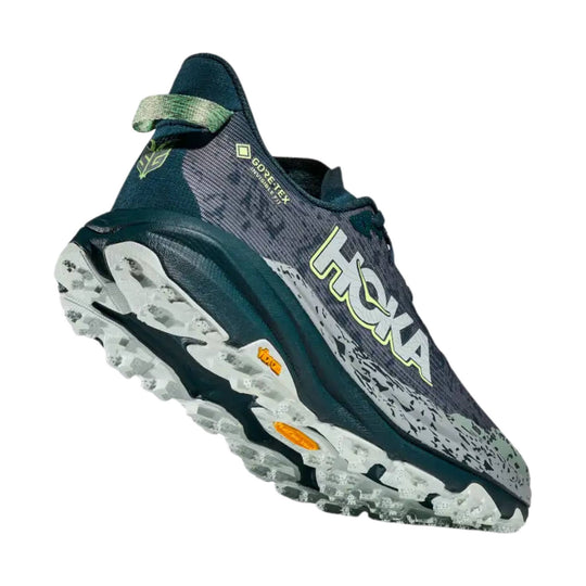 Dark trail running shoe with a rugged lugged sole, knit upper, and visible GORE-TEX and HOKA branding.