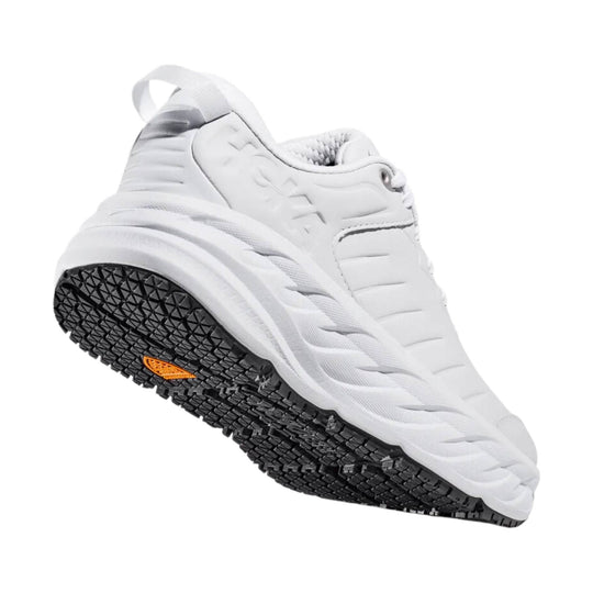 White athletic shoe with a black lugged outsole and orange accent, shown in side view