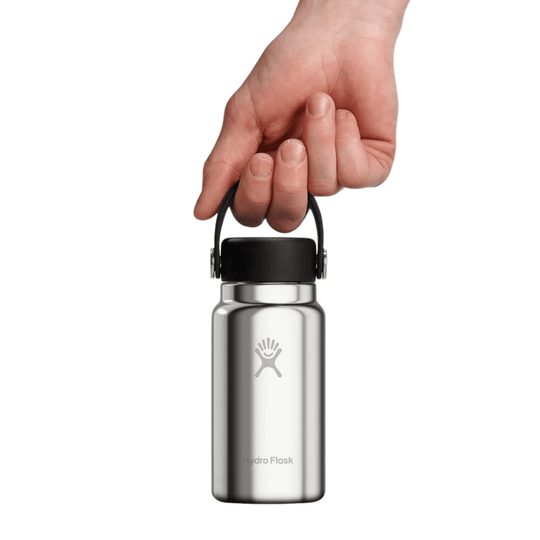 Stainless steel water bottle with black cap and loop handle, shown being held by a hand