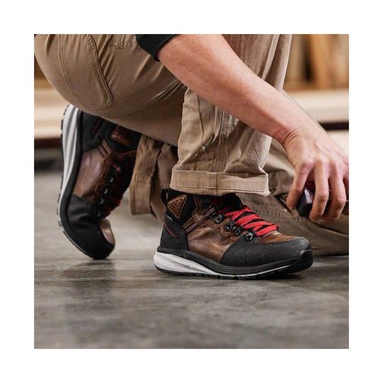 Brown and black mid-height work boot with red laces and a thick white-and-black sole