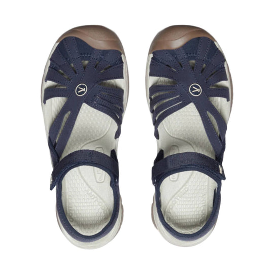 Pair of navy closed-toe sandals with tan toe caps, bungee straps, and white footbeds