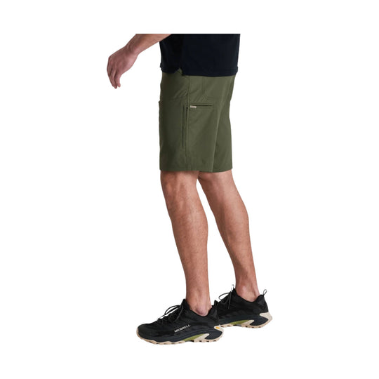 Olive green men’s athletic shorts shown on a model, side view, with zippered leg pocket