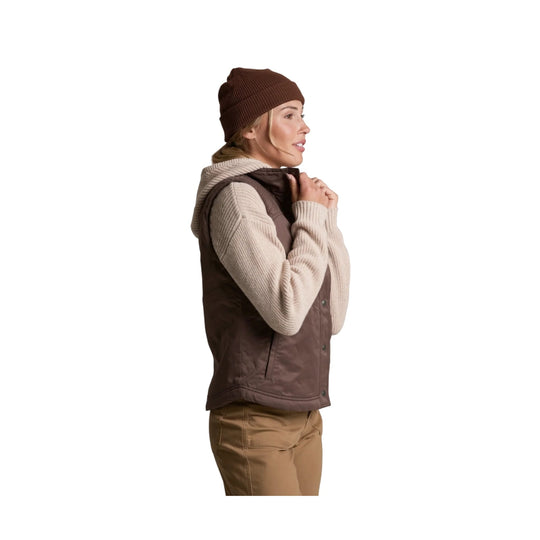 Woman in a brown quilted vest over a cream sweater, shown in side profile