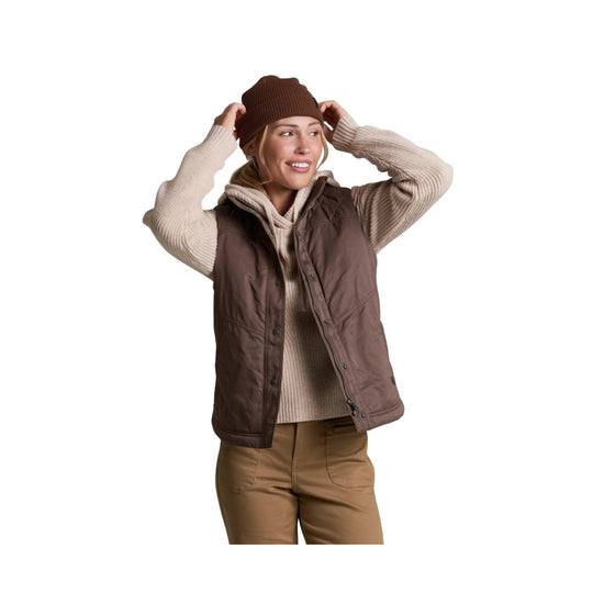 Brown lined vest worn over a beige ribbed sweater with tan pants and a knit beanie