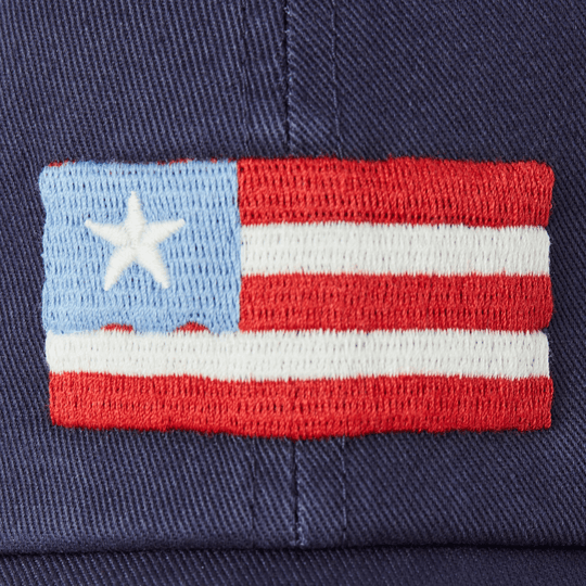 Close-up of a navy cap with an embroidered red, white, and light blue striped flag patch and white star