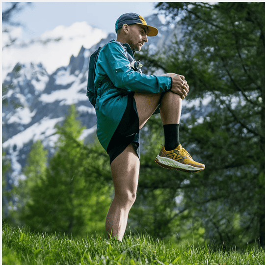 Yellow trail running shoe with black side logo and thick white midsole, shown on a runner outdoors