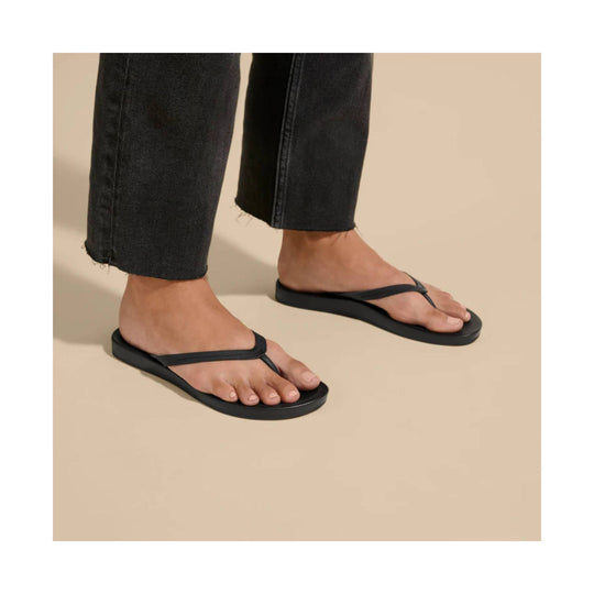 Black thong sandals on a model wearing cropped black pants