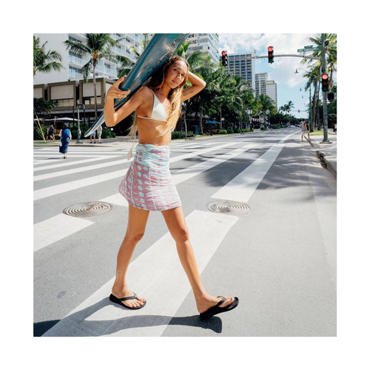 Black thong-style sandals worn with a skirt in a street scene