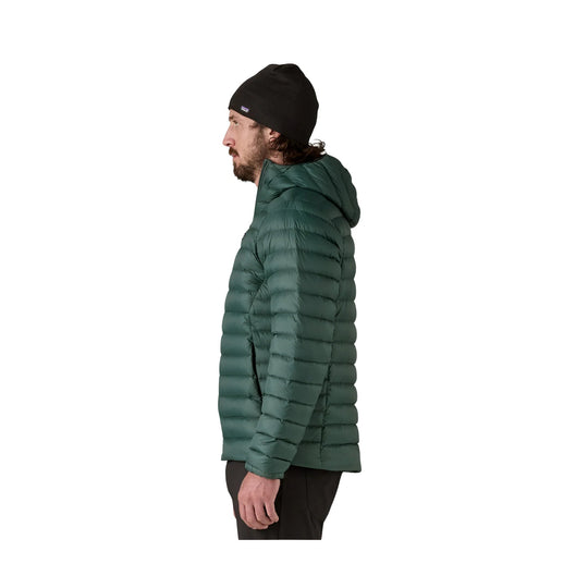 Green quilted puffer jacket with hood, shown in side profile on a model