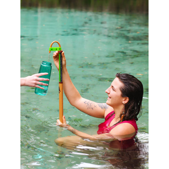 Portable water filter with a hose filling a reusable bottle in a stream