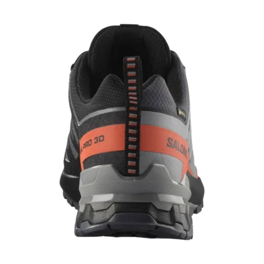Black and gray trail running shoe shown from the back with orange heel branding and a pull tab