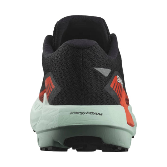 Black trail running shoe with mint-green midsole and orange accents, rear view