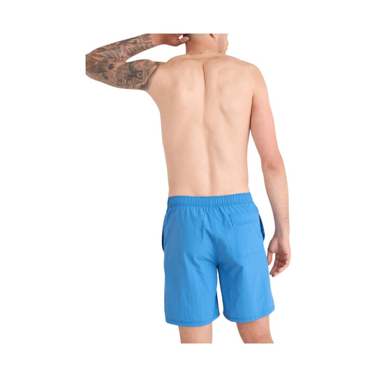 Man modeling bright blue swim trunks, shown from the back