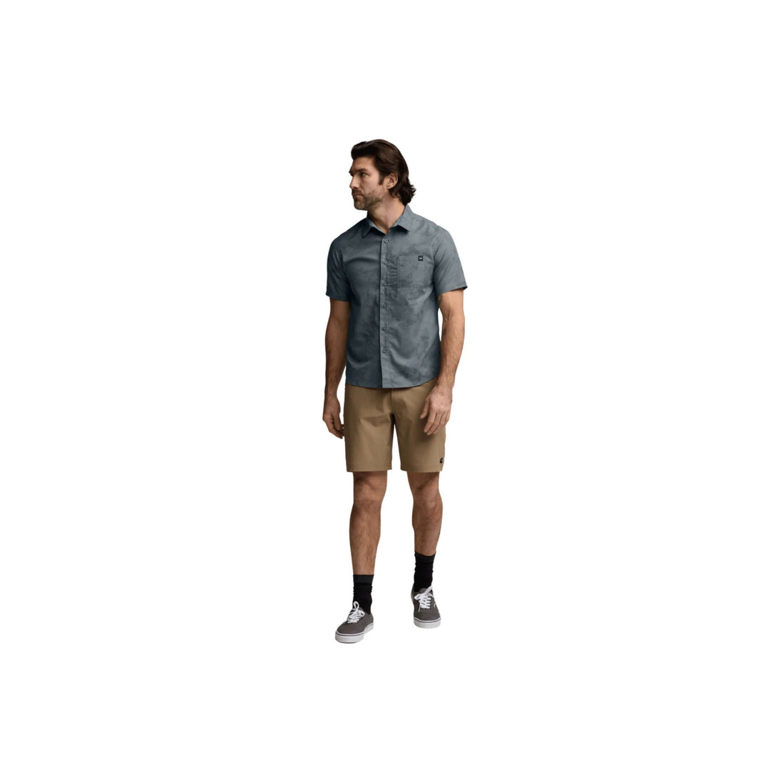 Men's short-sleeve button-up shirt in muted blue-gray with tan shorts, black socks, and gray sneakers