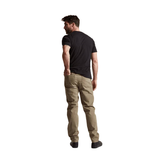 Tan five-pocket pants shown from the back on a model wearing a black T-shirt