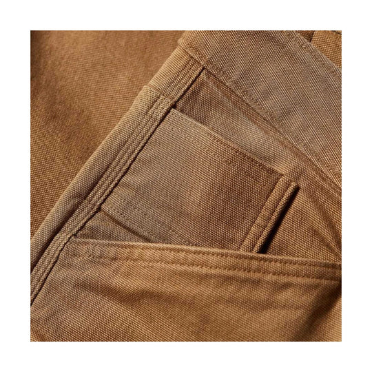 Close-up of brown woven pants with topstitching and a zippered pocket