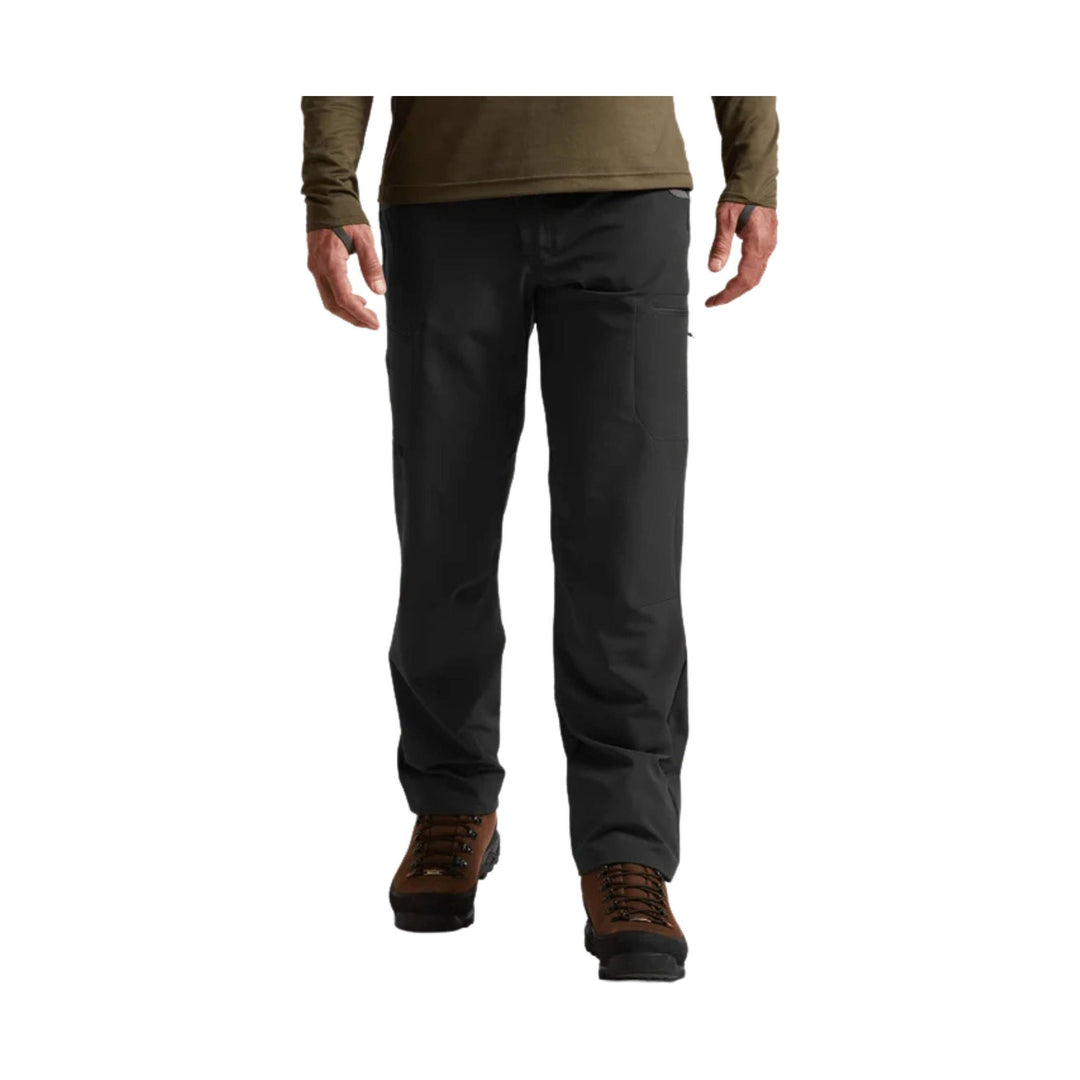 Black hiking pants shown on a standing model with brown hiking boots