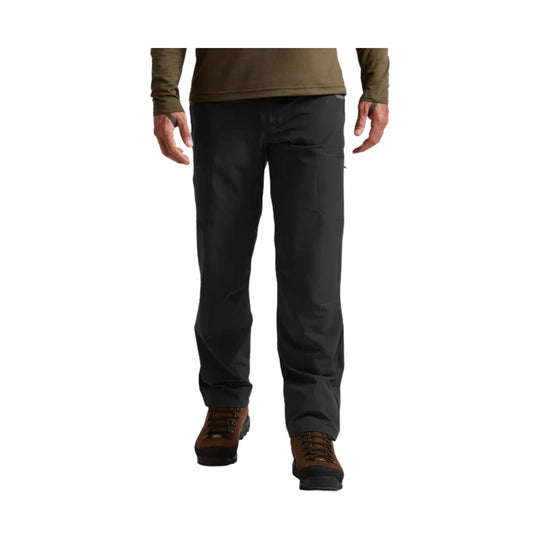 Black hiking pants shown on a standing model with brown hiking boots