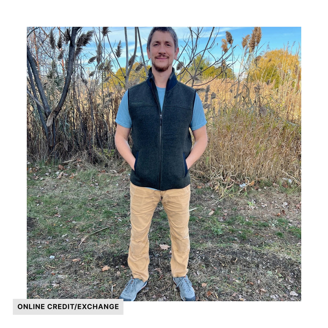 Dark fleece zip-up vest with a high collar and front pockets, shown on a man outdoors