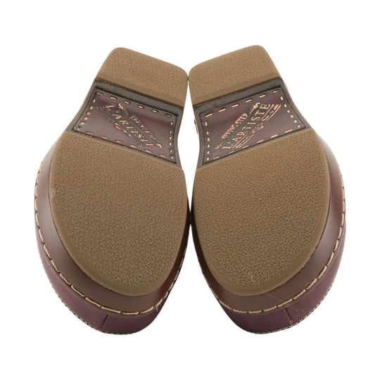 Brown clog outsoles with textured tan tread and visible L'ARTISTE branding