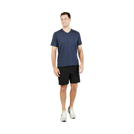 Model wearing a heathered navy V-neck T-shirt with black shorts and white sneakers