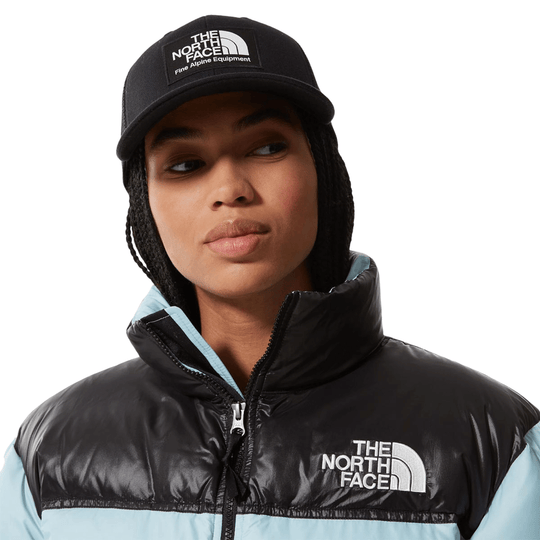 Black North Face cap and puffer vest with light blue sleeves, shown on a model