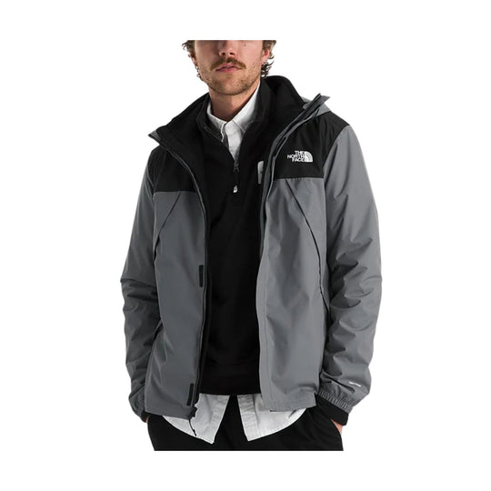 Gray and black hooded jacket with a chest logo, shown over a black quarter-zip top and white button-up shirt.