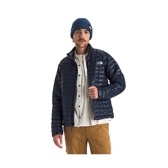 Dark navy quilted puffer jacket with a small chest logo, worn over a cream button-up shirt