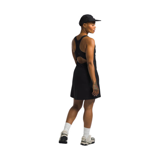 Black sleeveless athletic dress with open racerback, worn with cap, socks, and trail shoes