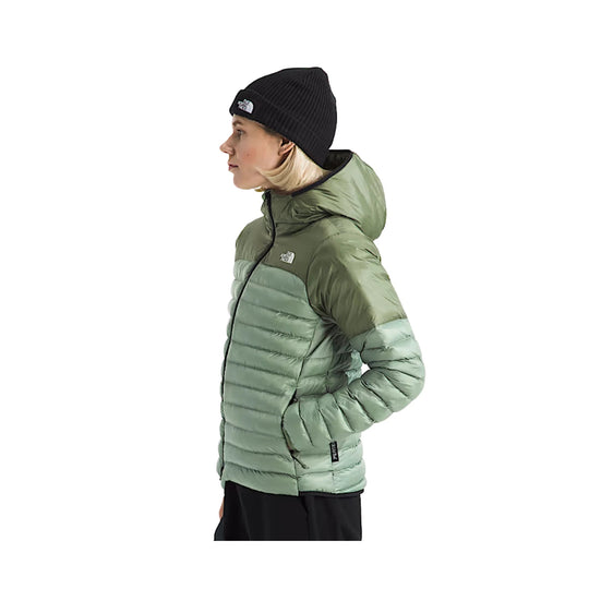Side view of a two-tone hooded puffer jacket with black beanie and visible The North Face logos