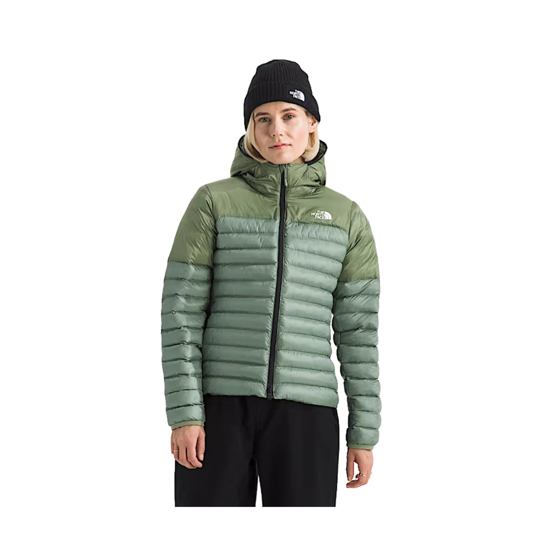 Sage green quilted hooded puffer jacket with black zipper, worn with a black beanie