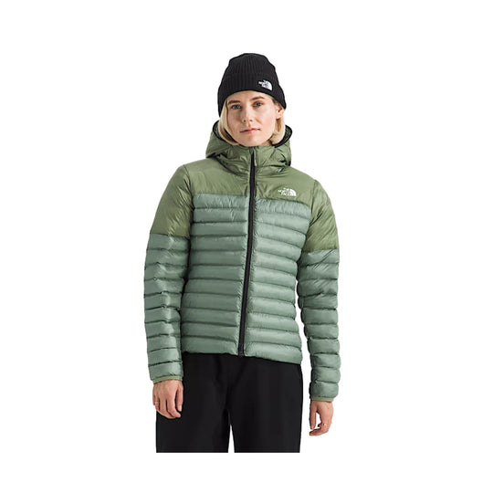 Sage green quilted hooded puffer jacket with black zipper, worn with a black beanie