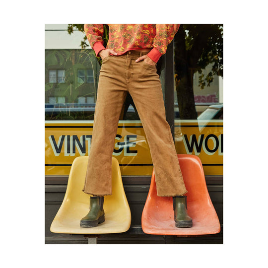 Honey brown flared corduroy pants with raw hems and olive green boots.