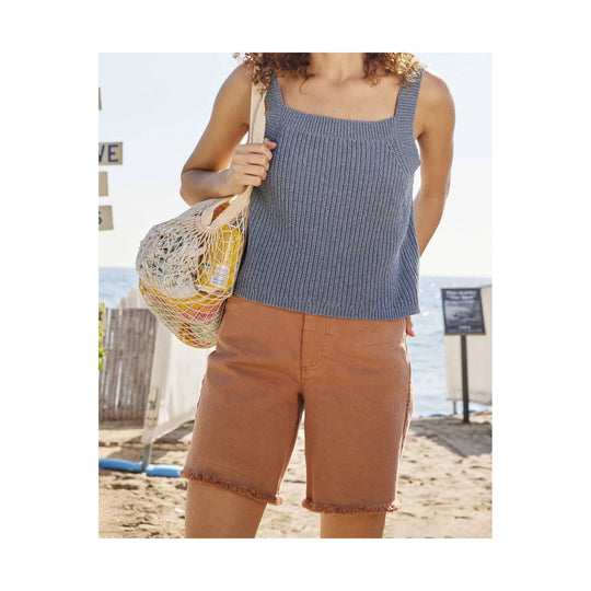 Brown cutoff shorts with frayed hems, shown on a model at the beach