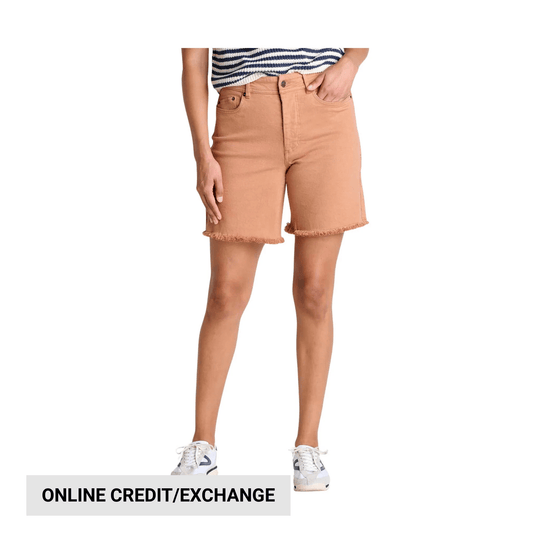 Tan frayed hem cutoff shorts worn with a striped top and white sneakers